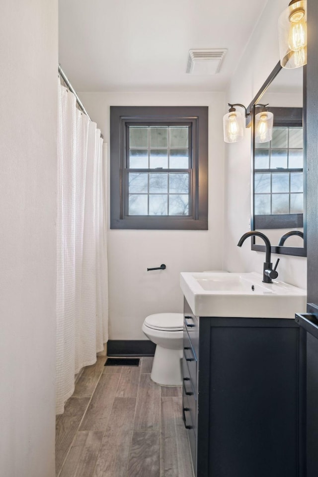 bathroom with a wealth of natural light, toilet, and vanity