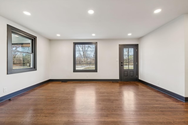 empty room with dark hardwood / wood-style floors and a wealth of natural light