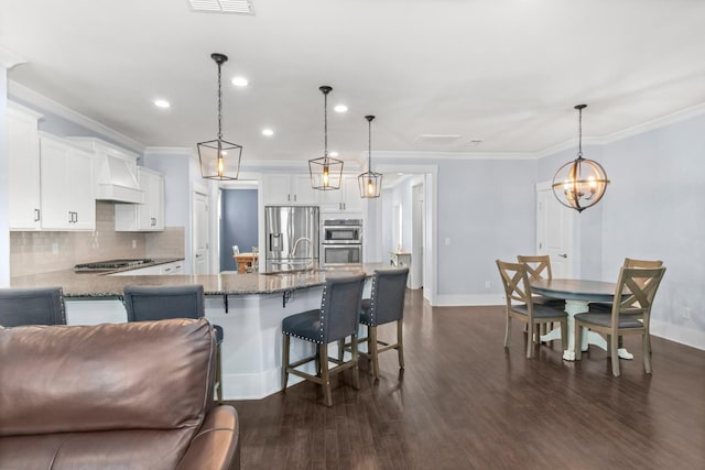 kitchen featuring stainless steel appliances, white cabinetry, ornamental molding, and decorative light fixtures