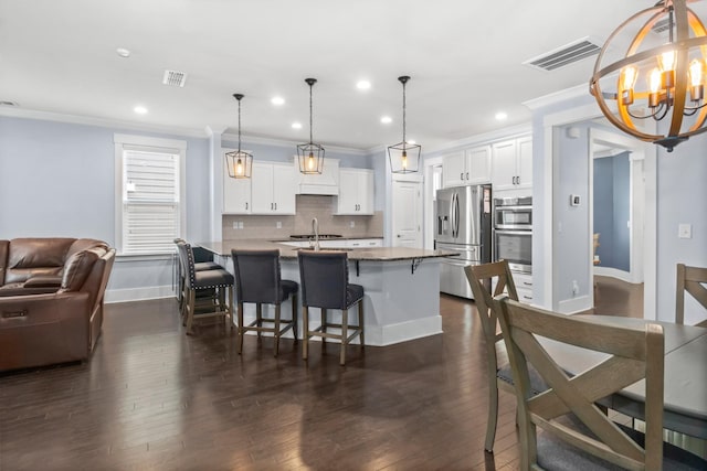 kitchen featuring white cabinetry, a kitchen island with sink, stainless steel refrigerator with ice dispenser, pendant lighting, and a breakfast bar area