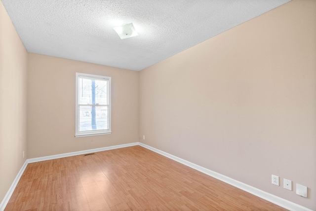 spare room with a textured ceiling and light hardwood / wood-style flooring