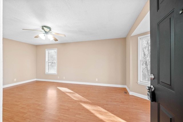 empty room with ceiling fan, a textured ceiling, and light hardwood / wood-style floors