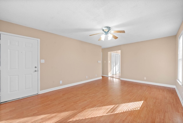 empty room with a textured ceiling, ceiling fan, and light hardwood / wood-style floors