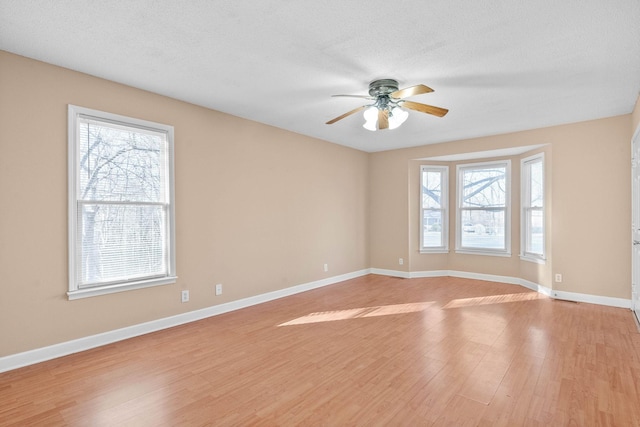 empty room featuring ceiling fan, a textured ceiling, and light hardwood / wood-style flooring