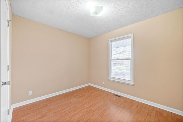 unfurnished room with a textured ceiling and wood-type flooring