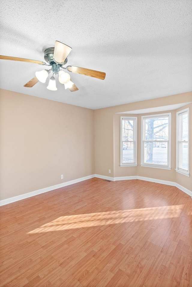 unfurnished room with a textured ceiling, ceiling fan, and light hardwood / wood-style flooring