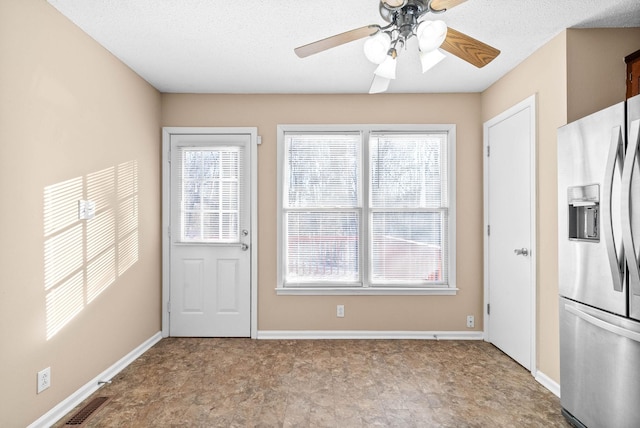 doorway with ceiling fan and a textured ceiling