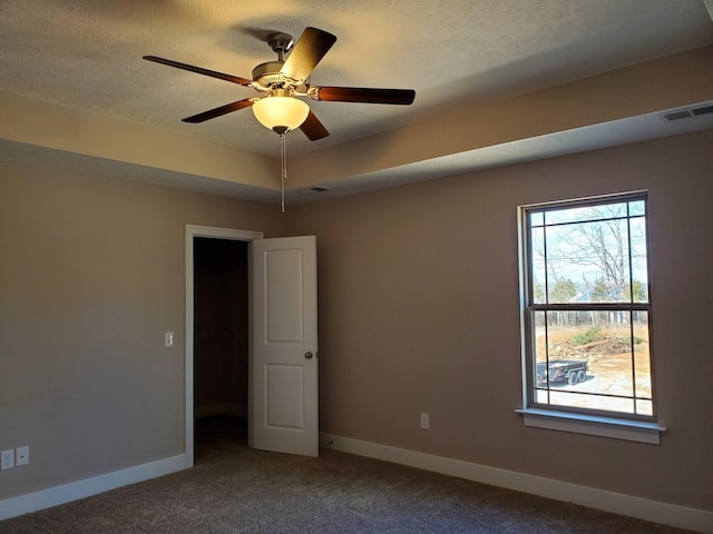 carpeted spare room featuring ceiling fan, a textured ceiling, and a raised ceiling