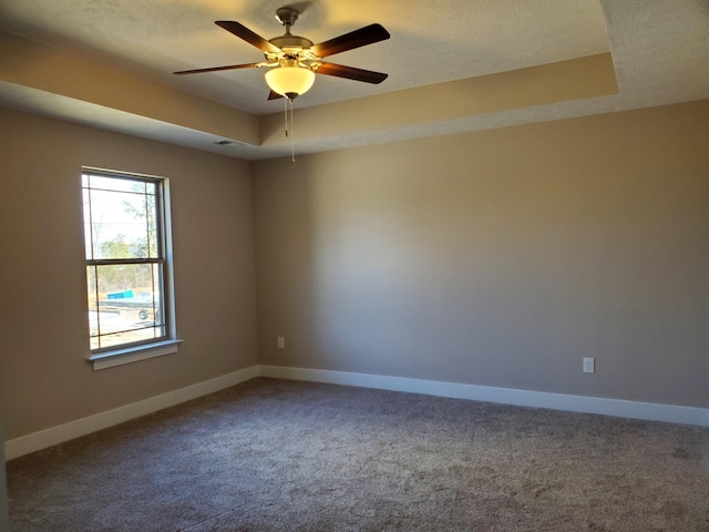 carpeted empty room featuring ceiling fan and a tray ceiling