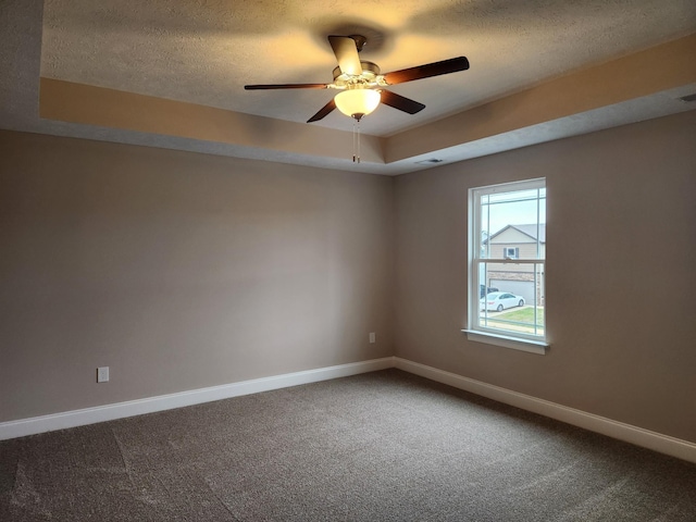 unfurnished room featuring carpet floors, a textured ceiling, a tray ceiling, and ceiling fan