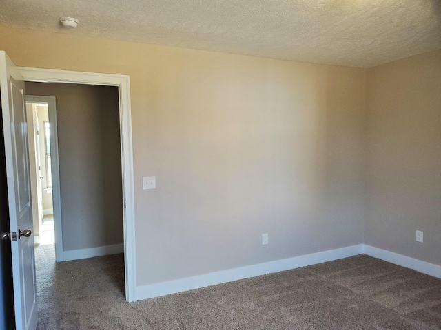 spare room with a textured ceiling and dark colored carpet