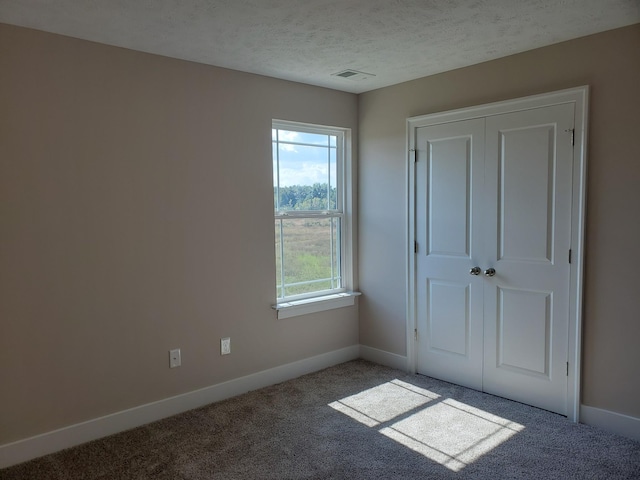 unfurnished bedroom with a closet, a textured ceiling, and carpet flooring