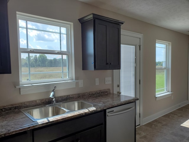 kitchen featuring sink, a wealth of natural light, stainless steel dishwasher, and a textured ceiling