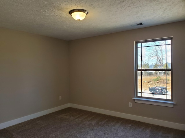 unfurnished room with a textured ceiling and dark colored carpet