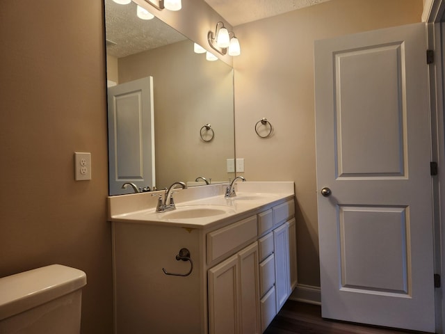 bathroom featuring a textured ceiling, toilet, hardwood / wood-style flooring, and vanity