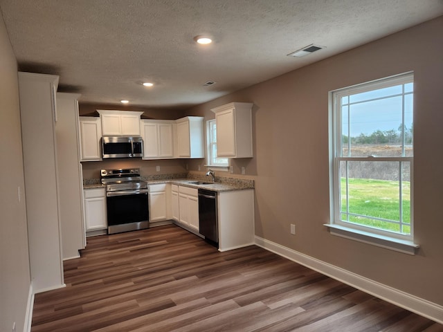 kitchen with white cabinets, appliances with stainless steel finishes, sink, and dark hardwood / wood-style floors