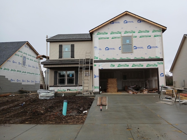 property under construction featuring an attached garage and concrete driveway