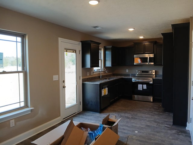 kitchen featuring dark wood-style floors, visible vents, appliances with stainless steel finishes, a sink, and baseboards