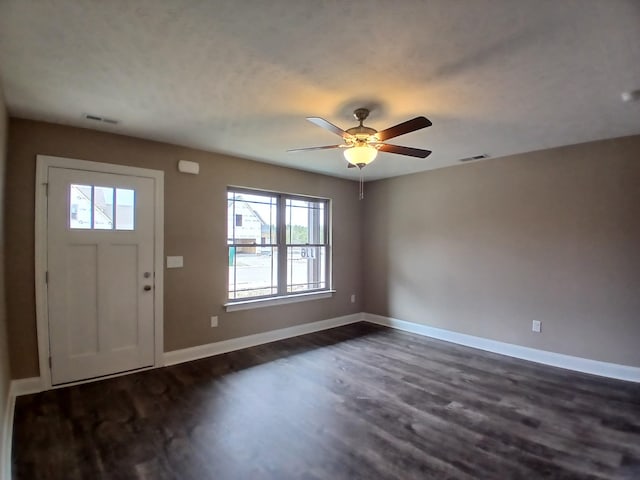 foyer entrance with visible vents, baseboards, dark wood-type flooring, and ceiling fan