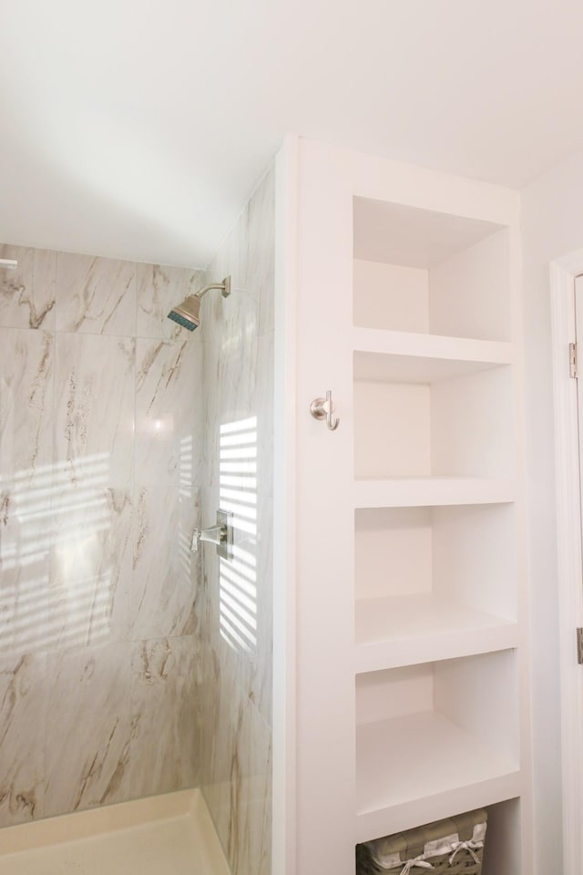 bathroom with a tile shower and built in features