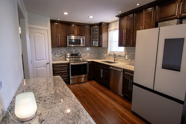 kitchen with dark hardwood / wood-style floors, sink, dark brown cabinetry, light stone countertops, and stainless steel appliances