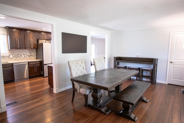 dining area with dark wood-type flooring and crown molding