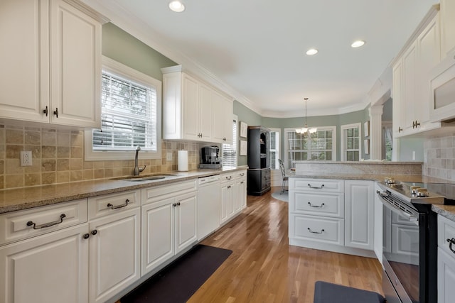 kitchen with white appliances, white cabinetry, sink, backsplash, and hanging light fixtures