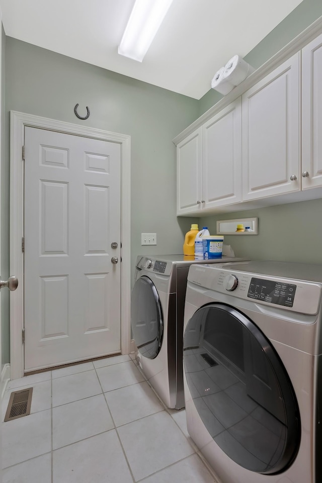 laundry area with light tile patterned flooring, cabinets, and washer and dryer