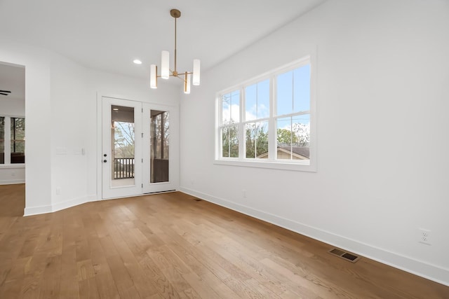 unfurnished dining area with a chandelier and hardwood / wood-style flooring