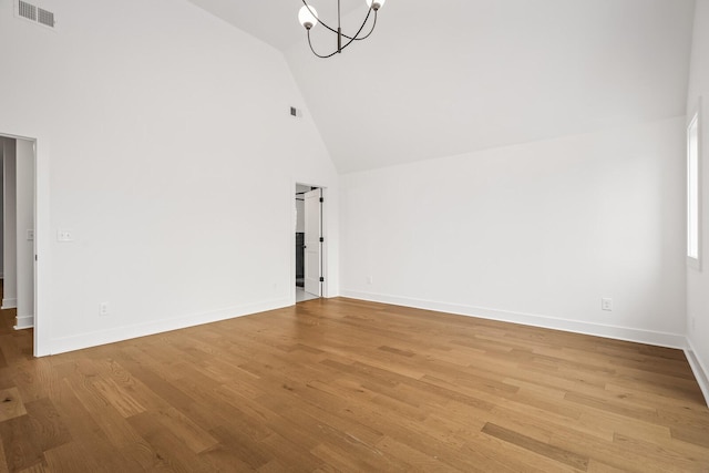 unfurnished living room with high vaulted ceiling, wood-type flooring, and an inviting chandelier