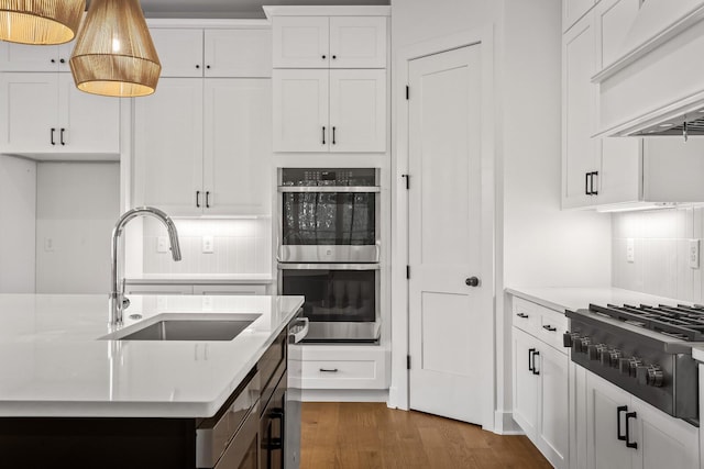 kitchen featuring custom exhaust hood, stainless steel appliances, tasteful backsplash, white cabinets, and sink