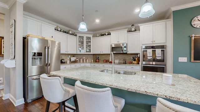 kitchen with stainless steel appliances, white cabinetry, crown molding, and decorative light fixtures