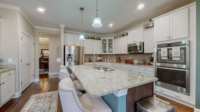 kitchen with appliances with stainless steel finishes, decorative light fixtures, sink, and a center island with sink