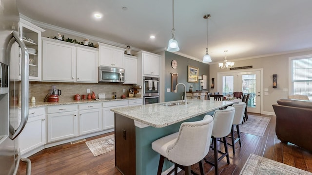 kitchen with decorative light fixtures, white cabinetry, sink, stainless steel appliances, and light stone countertops