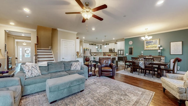 living room with dark hardwood / wood-style flooring, ceiling fan with notable chandelier, and ornamental molding