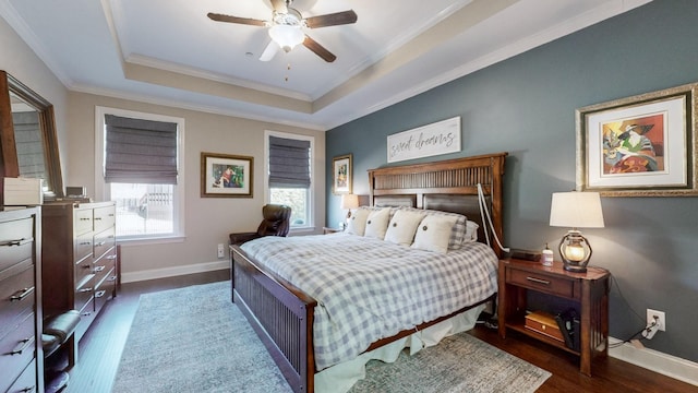 bedroom featuring a tray ceiling, ornamental molding, dark hardwood / wood-style floors, and ceiling fan