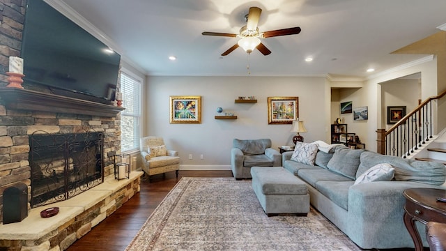 living room with crown molding, a stone fireplace, dark wood-type flooring, and ceiling fan