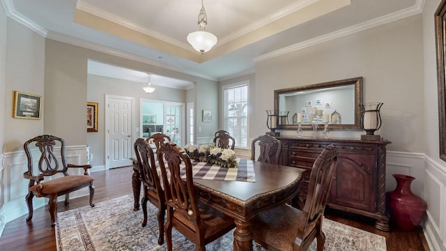 dining space with a raised ceiling, ornamental molding, and dark hardwood / wood-style floors