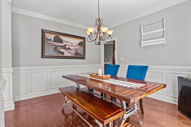 dining area featuring a notable chandelier, wood-type flooring, and ornamental molding