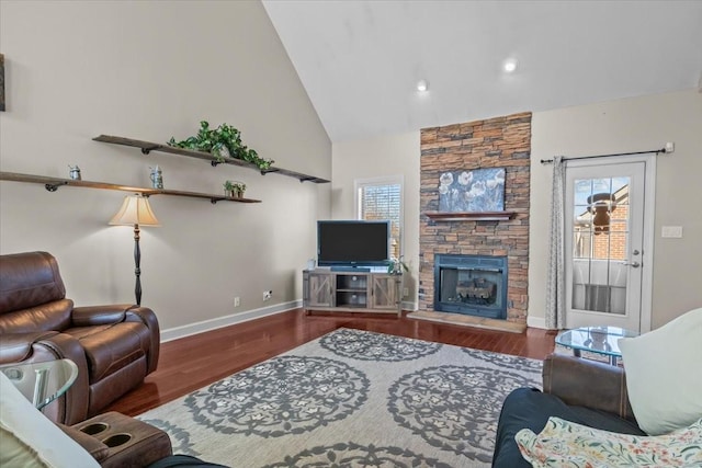 living room featuring dark hardwood / wood-style floors, a stone fireplace, and high vaulted ceiling