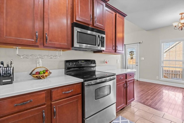 kitchen with light tile patterned flooring, appliances with stainless steel finishes, and a notable chandelier