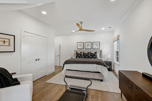 bedroom with crown molding, light hardwood / wood-style floors, a closet, and ceiling fan