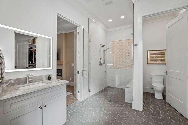 bathroom featuring crown molding, vanity, toilet, and a shower with door