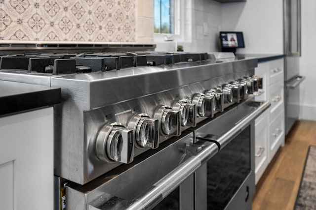 room details featuring range with two ovens, wood-type flooring, and backsplash