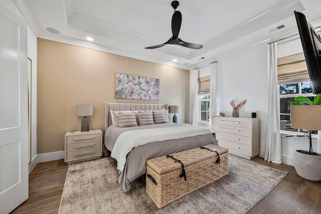 bedroom featuring crown molding, wood-type flooring, a raised ceiling, and ceiling fan