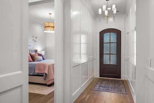 entrance foyer with crown molding, dark hardwood / wood-style flooring, and a notable chandelier