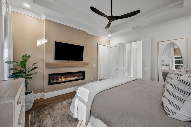 bedroom with crown molding, ceiling fan, dark hardwood / wood-style flooring, and a raised ceiling