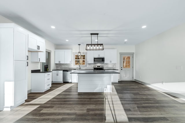 kitchen with a center island, pendant lighting, dark wood-type flooring, appliances with stainless steel finishes, and white cabinets