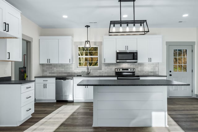 kitchen featuring stainless steel appliances, decorative backsplash, white cabinets, and decorative light fixtures