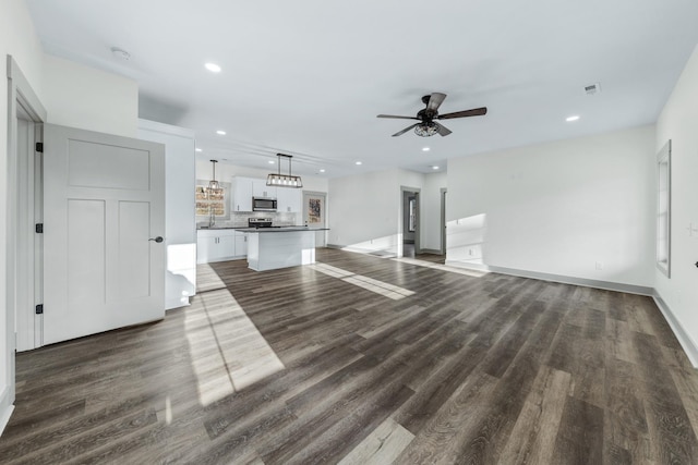 unfurnished living room featuring ceiling fan and dark hardwood / wood-style flooring